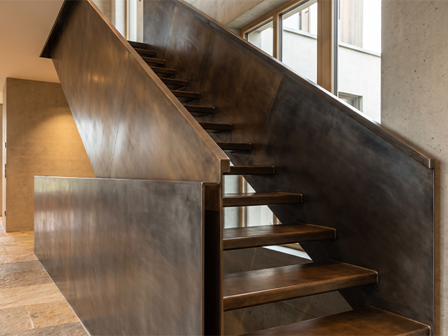 Escalier métallique sur mesure avec finition acier patiné brun et marches assorties dans un intérieur contemporain