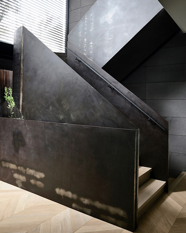 Escalier sur mesure en acier avec limons métalliques pleins et finition patinée dans un intérieur contemporain