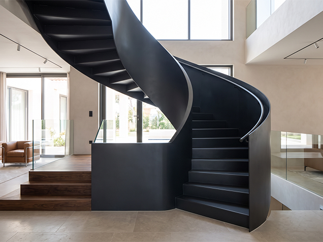 Escalier hélicoïdal sur mesure en acier noir avec finition thermolaquée mate dans un intérieur contemporain