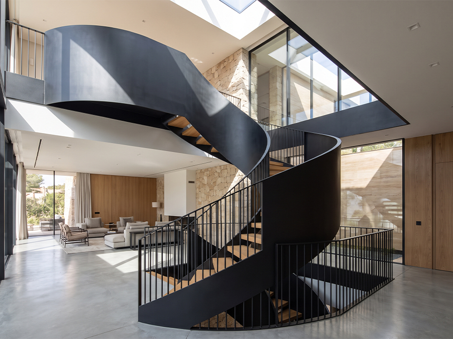 Escalier hélicoïdal sur mesure en acier noir avec marches en bois intégré au double volume d’une villa contemporaine