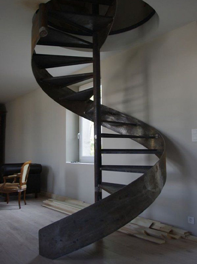 Escalier colimaçon métallique sur mesure avec marches tournantes organisées autour d’un noyau central