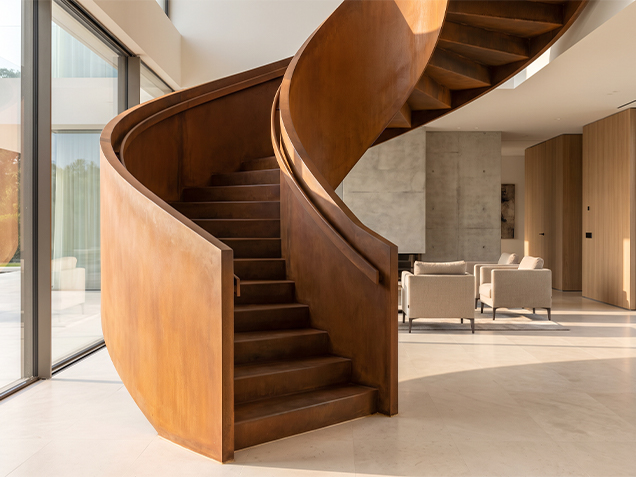 Escalier hélicoïdal sur mesure en acier Corten avec patine brune stabilisée dans un intérieur contemporain