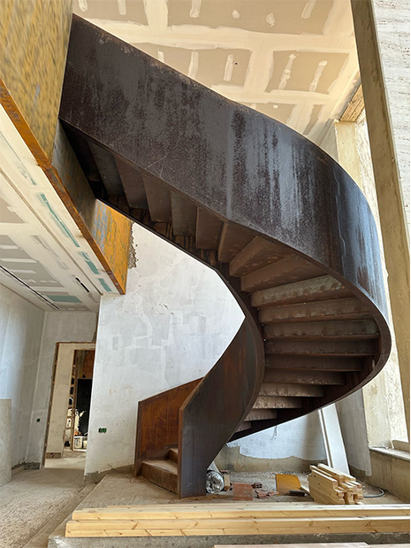 Escalier hélicoïdal métallique sur mesure installé dans un projet architectural en cours de finition