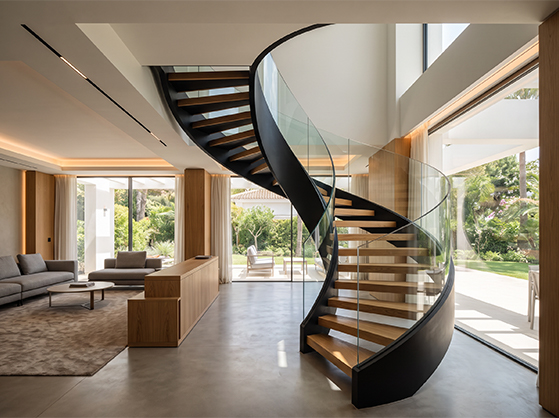 Escalier hélicoïdal sur mesure en acier noir avec marches en bois et garde-corps en verre dans une villa contemporaine