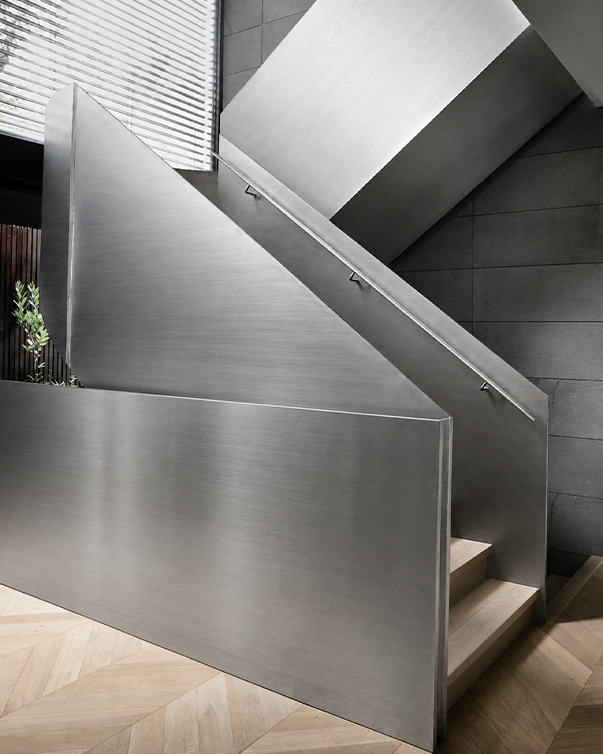 Escalier sur mesure avec habillage en inox brossé et main courante métallique dans un intérieur contemporain