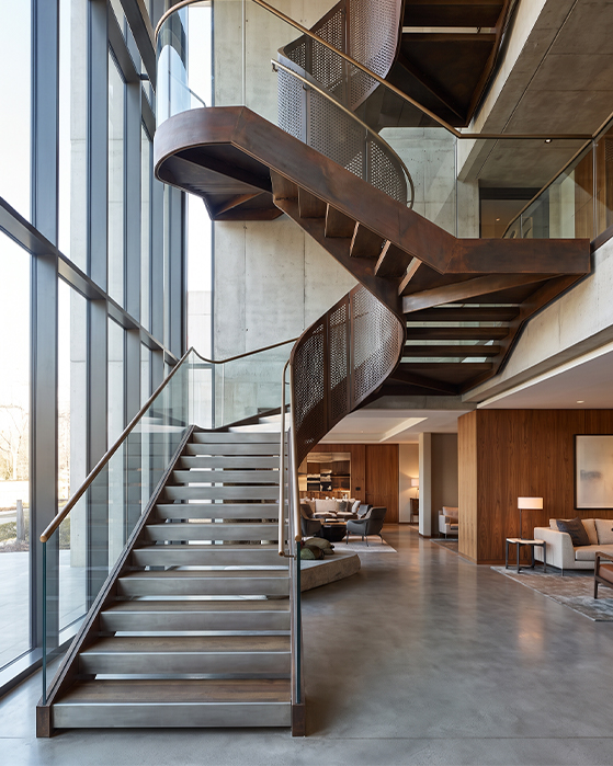 Escalier métallique courbe sur mesure avec garde-corps perforé dans une résidence contemporaine