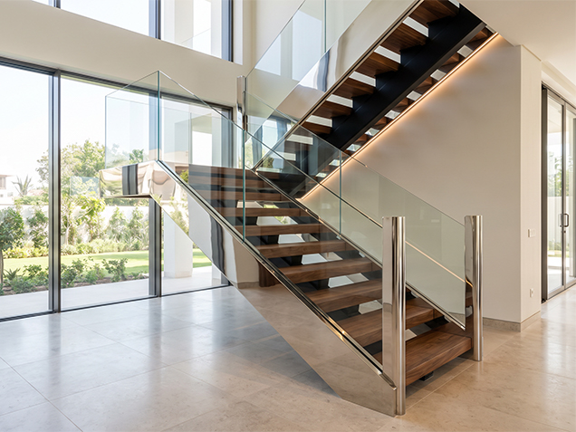 Escalier sur mesure avec marches en bois, garde-corps en verre et éléments métalliques à finition satinée brillante