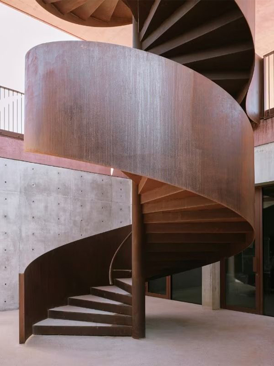 Escalier colimaçon métallique sur mesure avec marches rayonnantes organisées autour d’un noyau central