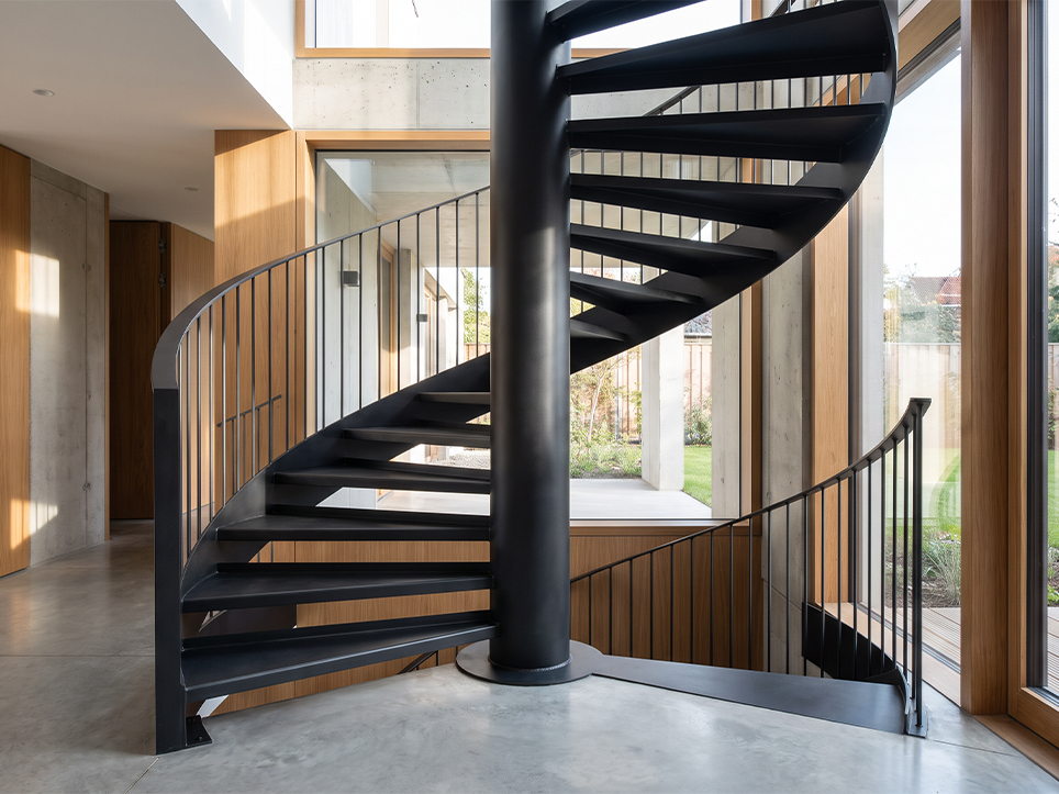 Escalier colimaçon métallique noir sur mesure avec marches rayonnantes fixées autour d’un noyau central en acier